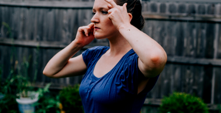 Dancer standing in the rainy backyard with her hands on her face