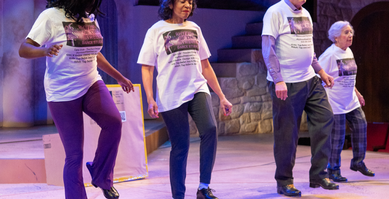 4 Tap dancers in a line dancing on stage wearing t-shirts and pants