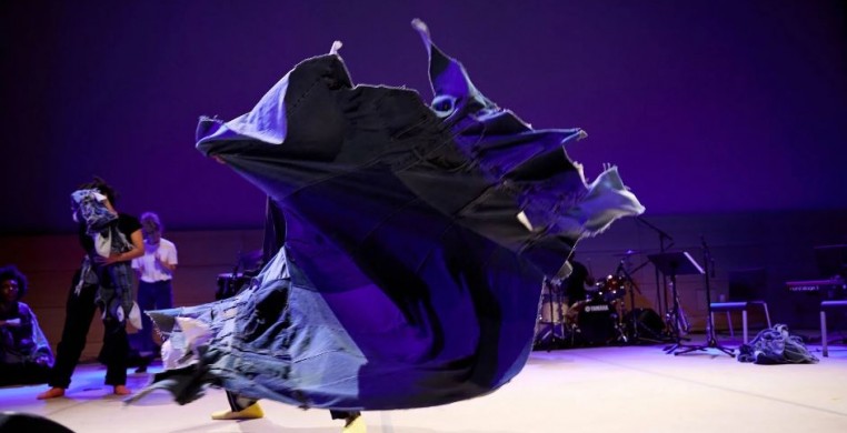 A dance performance featuring a blue tarp twisting in the air.