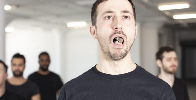 Photo of a performer with mouth open, showing rocks in their mouth.