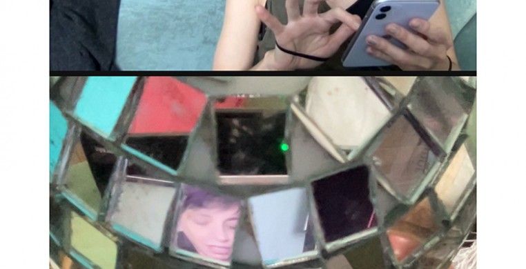 Fingers hovering over a phone above an array of square mirrors, one which reflects a face, others colors and light. 