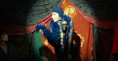 Performer seated in a spot light and holding a feather boa in hand 