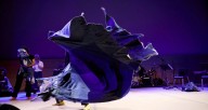 A dance performance featuring a blue tarp twisting in the air.