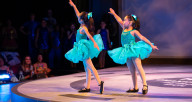 2 young girls dressed in green costumes performing a Ballet pose